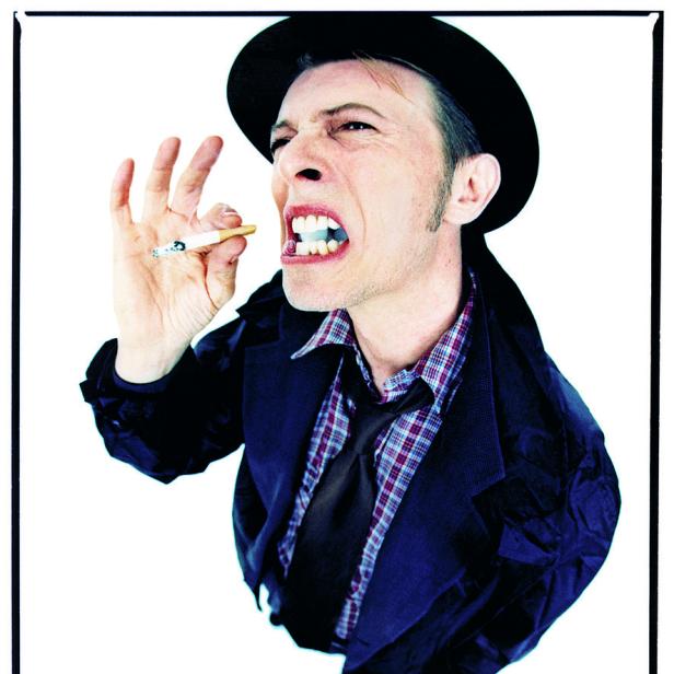 David Bowie mit Hut und Zigarette im Mund, die er mit den Fingern hält.