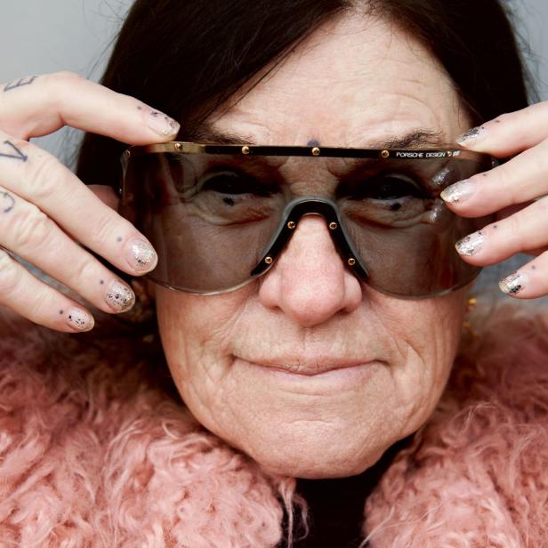 Eine Frau mit Tätowierungen auf den Händen trägt eine „Porsche Design“-Sonnenbrille.