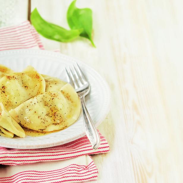 Auf einem Teller liegen goldbraune Maultaschen mit einer Gabel.