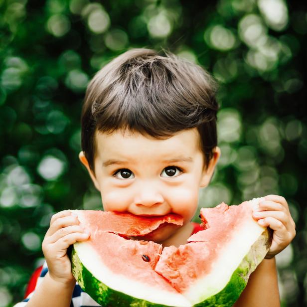 Ein kleiner Junge isst ein großes Stück Wassermelone.