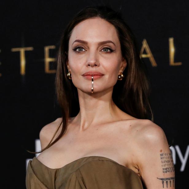 Angelina Jolie bei der Premiere von „Eternals“ mit einem goldenen Schmuckstück an der Lippe.