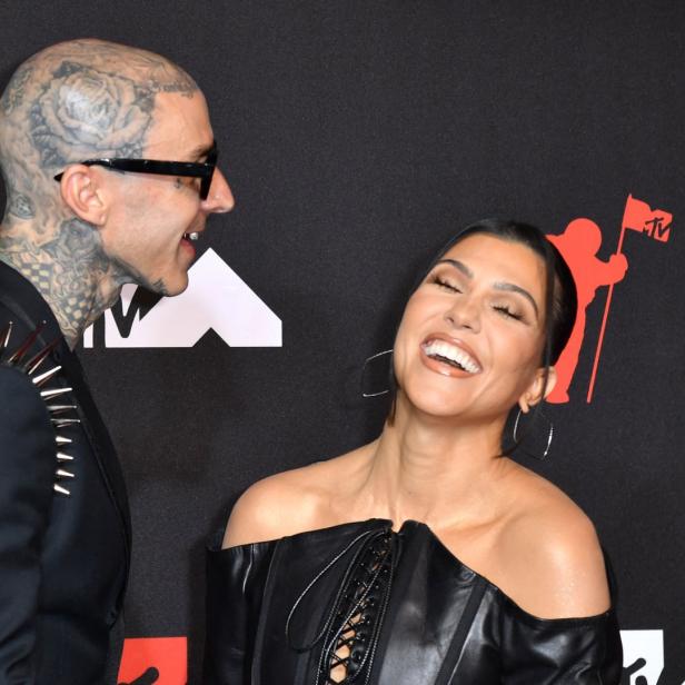 Kourtney Kardashian und Travis Barker lachen auf dem roten Teppich.