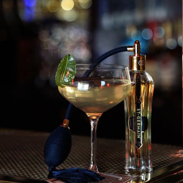 Ein Cocktail mit einer Flasche St-Germain-Likör auf einer Bar.