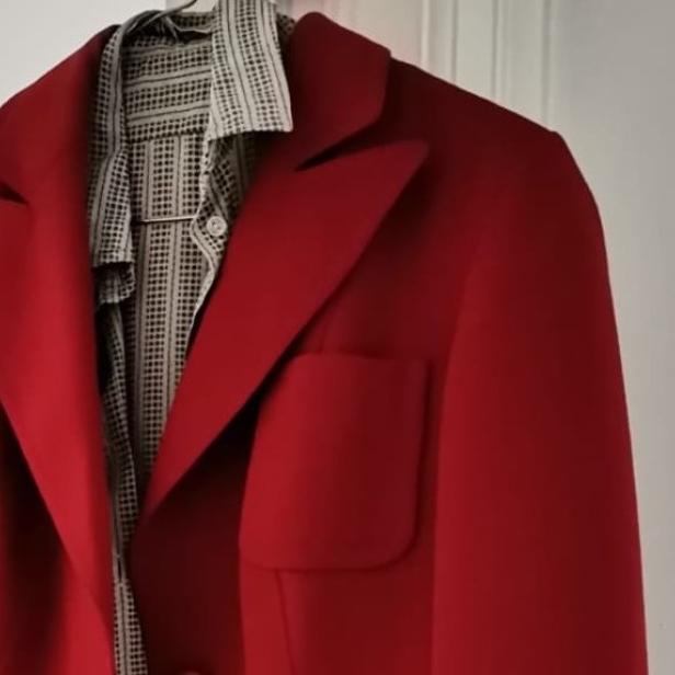 Ein roter Blazer hängt über einem Hemd mit Muster.