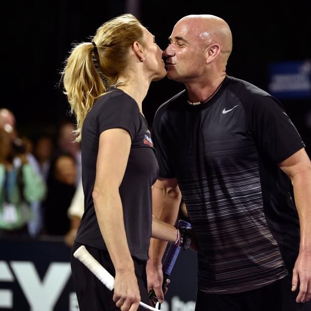 Steffi Graf und Andre Agassi küssen sich auf einem Tennisplatz.