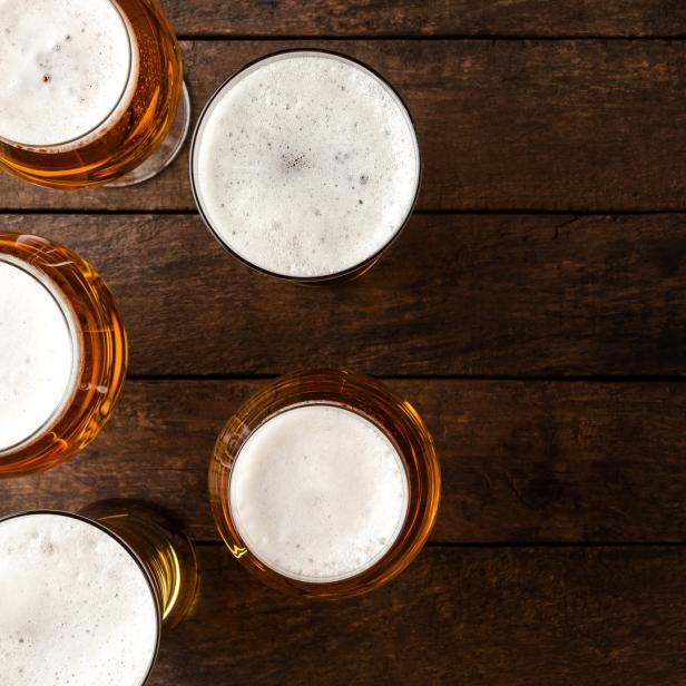 Mehrere Gläser Bier stehen auf einem dunklen Holztisch.