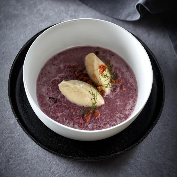 Eine Schüssel mit Rote-Bete-Suppe und zwei hellen Klößen, garniert mit Dill.