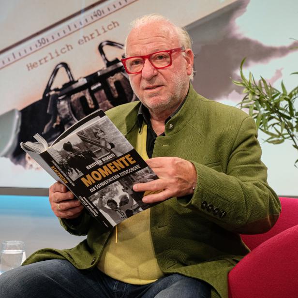 Ein Mann mit roter Brille liest das Buch „Momente der österreichischen Zeitgeschichte“ von Kristian Bissuti.
