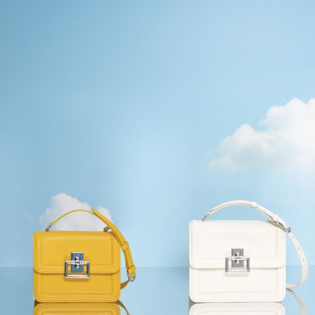 Drei Furla Handtaschen in Gelb, Weiß und Schwarz vor einem hellblauen Himmel mit Wolken.