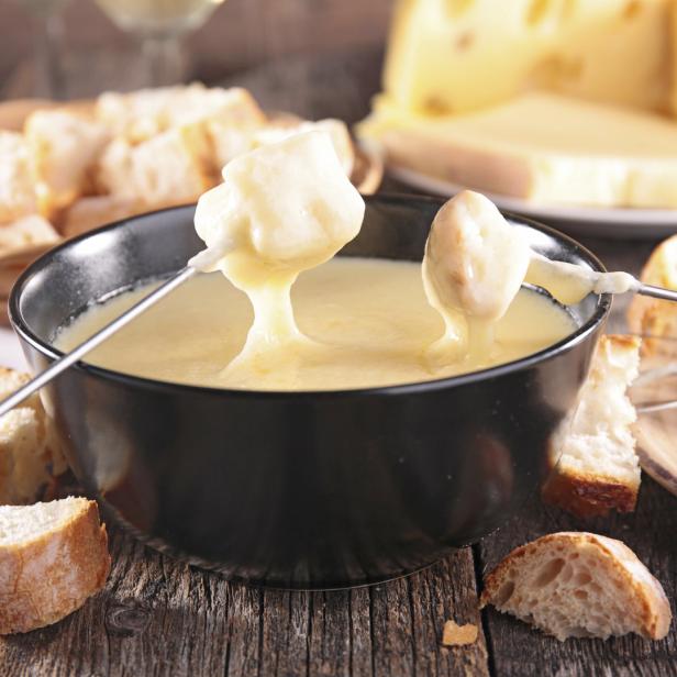 Ein Topf mit Käsefondue, umgeben von Brotstücken.