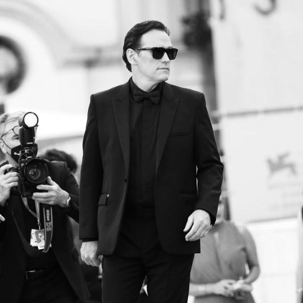 Quentin Tarantino in dunklem Anzug und Sonnenbrille auf einem roten Teppich.