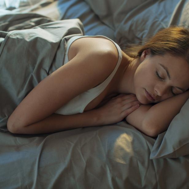 Eine junge Frau schläft friedlich in ihrem Bett.