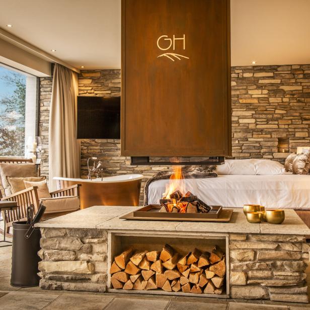 Ein luxuriöses Schlafzimmer mit Kamin, freistehender Badewanne und Blick ins Grüne.