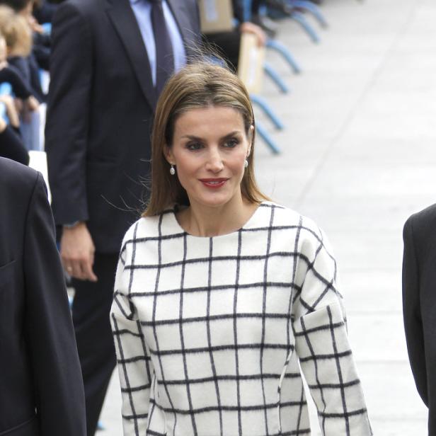 Königin Letizia mit einer roten Clutch und einem karierten Oberteil.