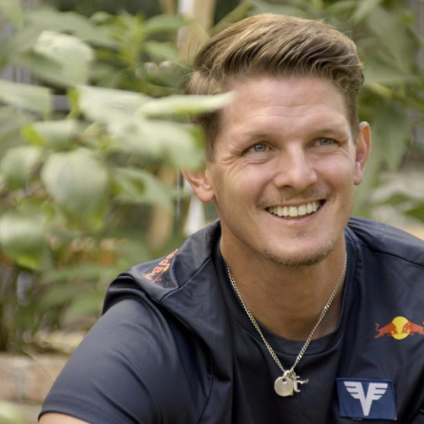 Thomas Morgenstern lächelt vor einem Hintergrund aus Pflanzen.