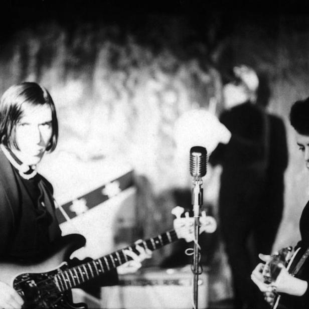 Ein Schwarzweißfoto von John Cale und Lou Reed bei einem Auftritt von The Velvet Underground.