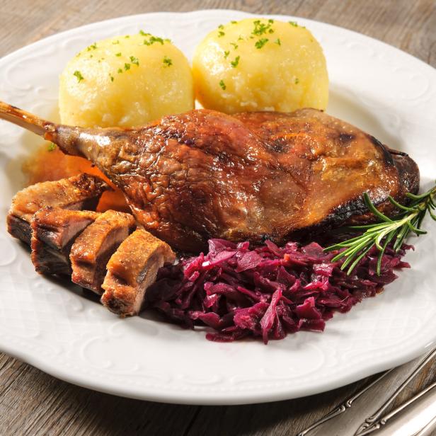 Ein Teller mit knuspriger Entenkeule, Kartoffelknödeln und Rotkohl.