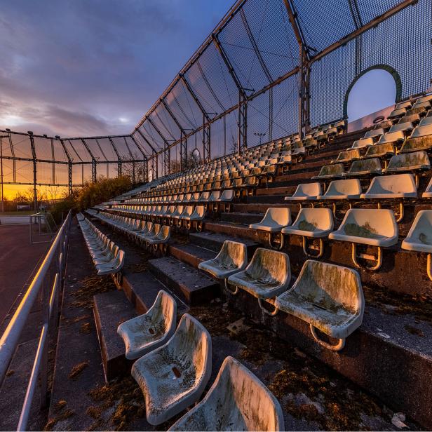 Verlassene Tribüne eines Sportplatzes bei Sonnenuntergang.
