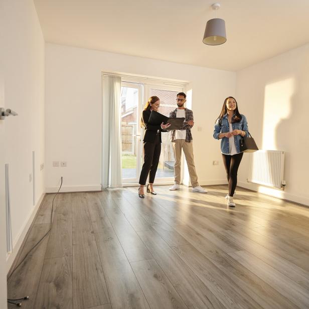 Ein Paar besichtigt mit einem Makler eine neue bzw. generalsanierte Wohnung