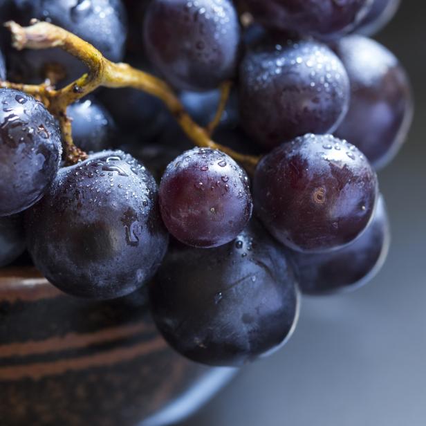 Nahaufnahme einer Traube blauer Weintrauben mit Wassertropfen.
