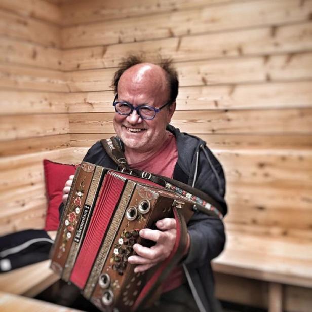 Ein Mann mit Brille spielt auf einer verzierten Harmonika.