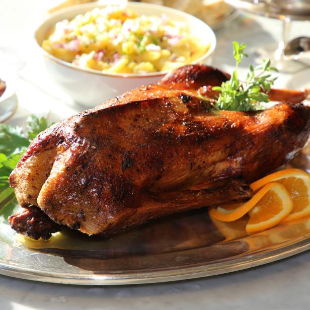 Ein gebratener Gänsebraten wird mit Orangenscheiben und Beilagen serviert.