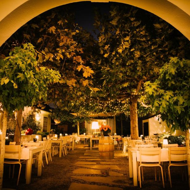 Ein Restaurant im Freien mit Tischen unter Bäumen, die mit Lichtern geschmückt sind.