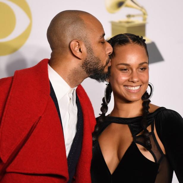 Alicia Keys lächelt, während ihr Mann sie auf die Wange küsst.