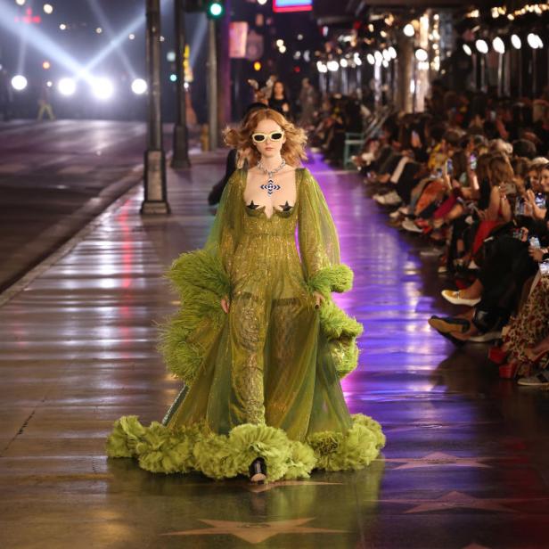 Ein Model in einem grünen Kleid mit Federn auf dem Hollywood Walk of Fame.