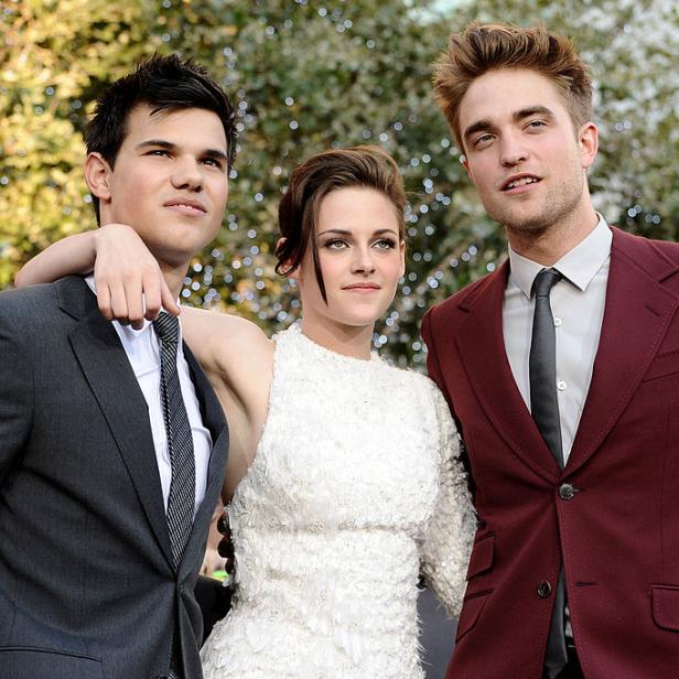 Taylor Lautner, Kristen Stewart und Robert Pattinson posieren zusammen auf einem roten Teppich.