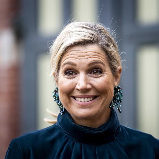 Königin Máxima lächelt und trägt auffällige Ohrringe.