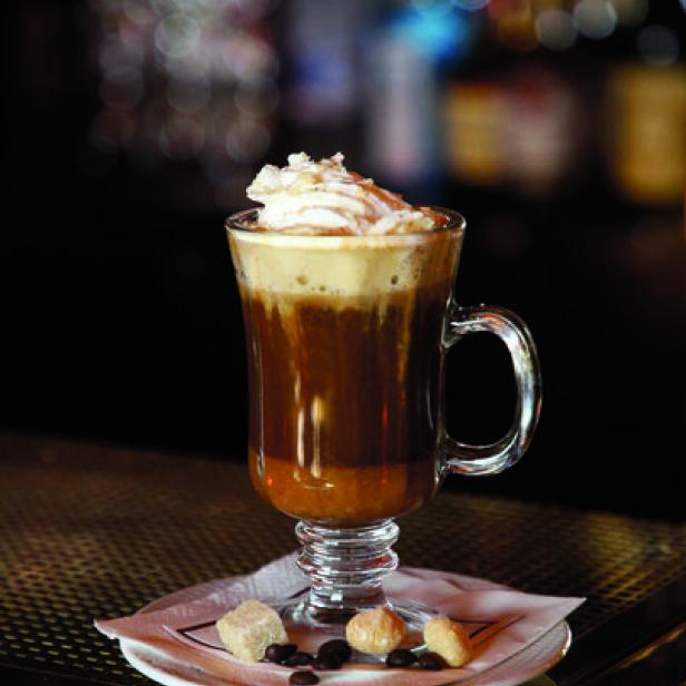 Ein Glas Irish Coffee mit Schlagsahne steht auf einem Tisch.