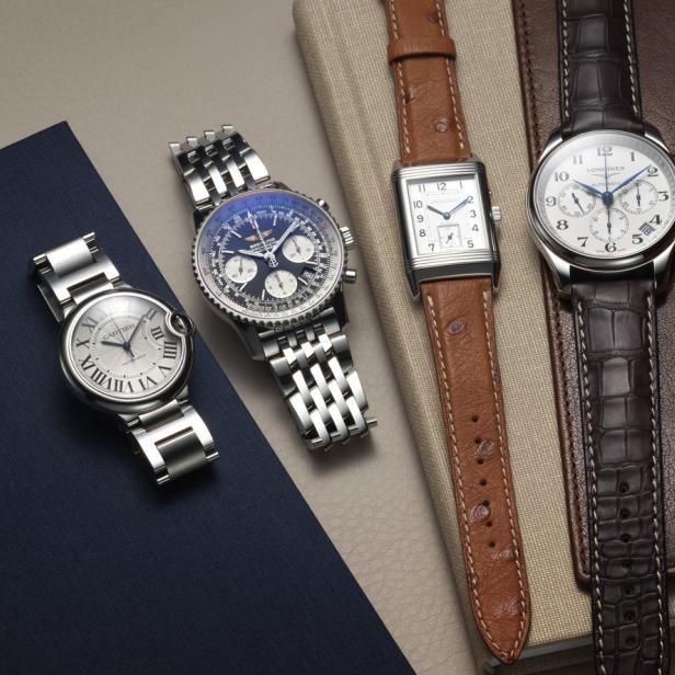 Vier verschiedene Herrenarmbanduhren der Marken Cartier, Breitling, Jaeger-LeCoultre und Longines liegen auf Notizbüchern.