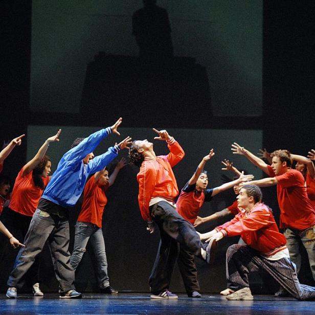 Eine Gruppe von Tänzern führt eine Choreografie auf einer Bühne auf.