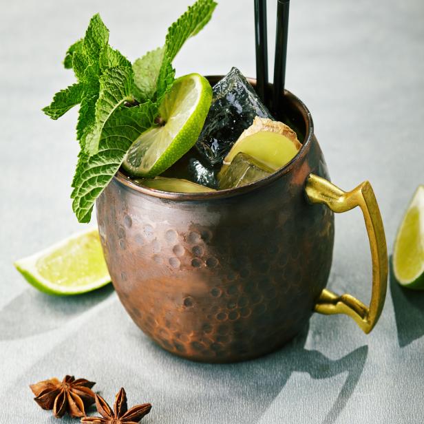 Ein Moscow Mule Cocktail in einem Kupferbecher mit Limette, Minze und Eiswürfeln garniert.