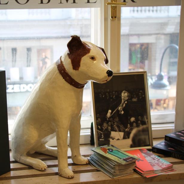 Eine Schaufensterdekoration mit einer Hundestatue, Büchern und einem gerahmten Foto.