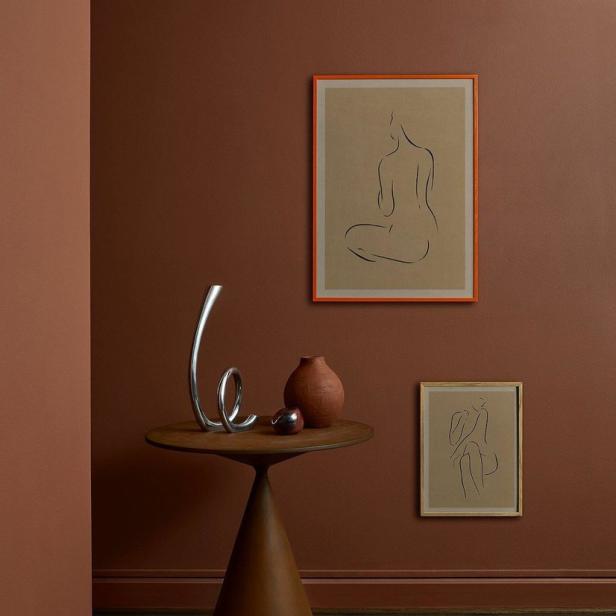 Ein Interieur mit einem kleinen Tisch, Vasen und zwei gerahmten Zeichnungen an der Wand.