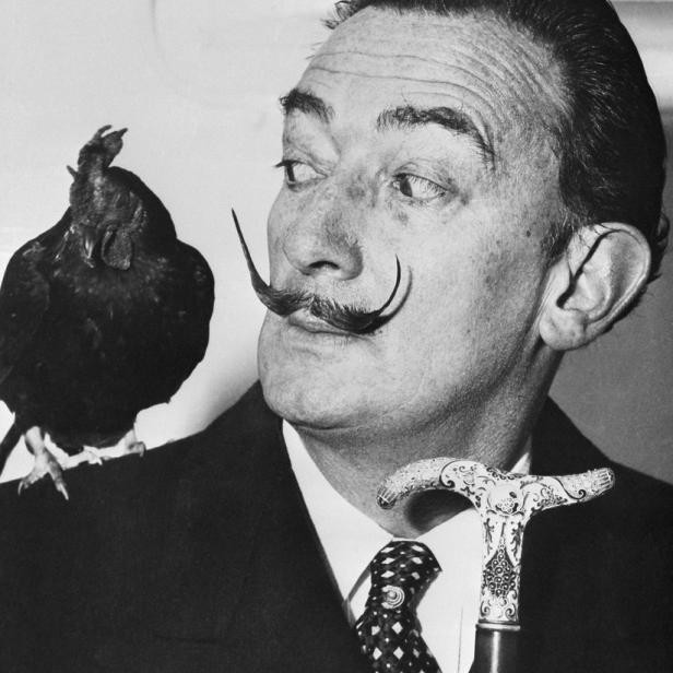 Salvador Dalí mit einem Huhn auf der Schulter und einem verzierten Spazierstock.