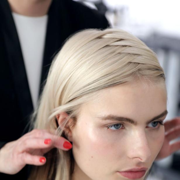 Eine Frau mit blonden Haaren wird von einem Stylisten frisiert.