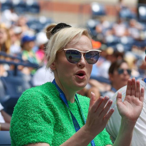 Eine Frau mit Sonnenbrille klatscht bei einer Sportveranstaltung Beifall.