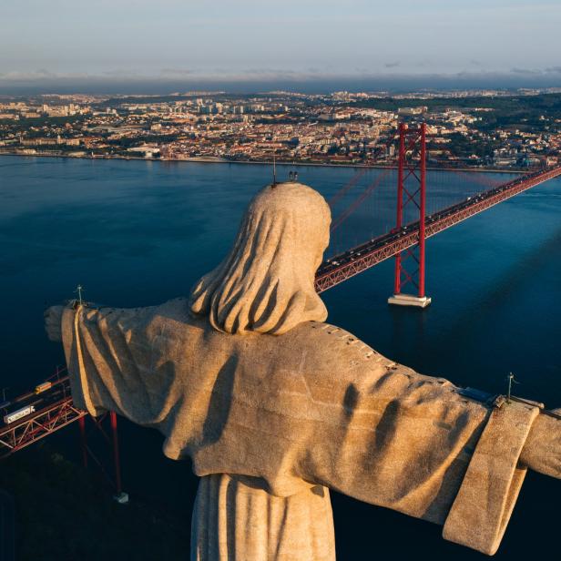Die Cristo Rei Statue mit der Brücke des 25. April im Hintergrund, Lissabon.