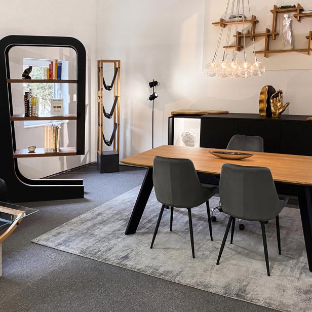 Ein Esszimmer mit einem Holztisch, grauen Stühlen und modernen Möbeln.