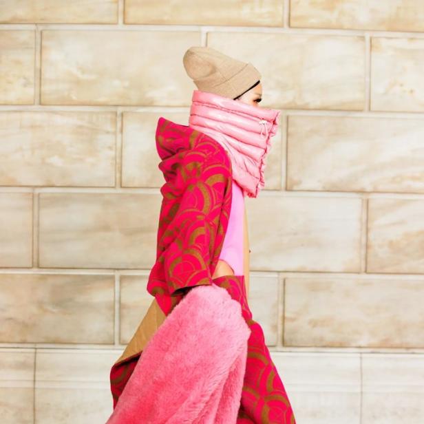 Ein Model präsentiert ein auffälliges Outfit in Pink und Gold mit passender Mütze.