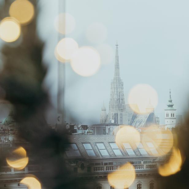 Blick auf Wien mit dem Stephansdom und Bokeh-Lichtern im Vordergrund.