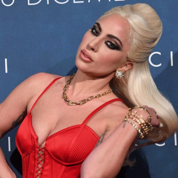 Lady Gaga in einem roten Kleid mit goldenen Accessoires.