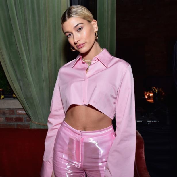 Hailey Bieber trägt ein rosa Outfit in einem Innenraum.