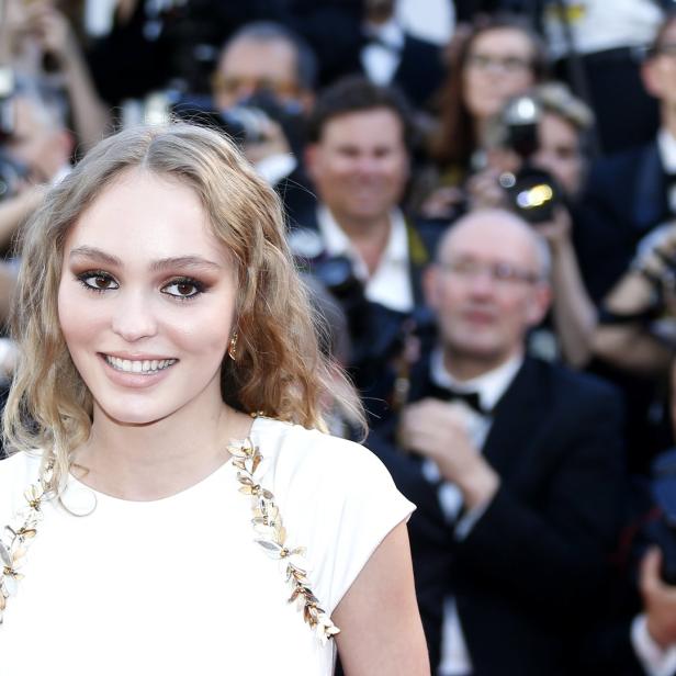 Lily-Rose Depp lächelt auf dem roten Teppich in die Kamera.