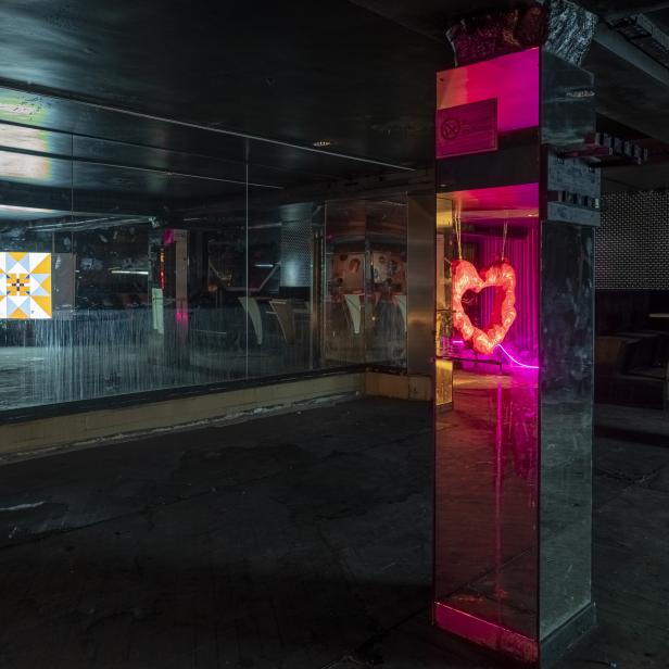 Ein verlassener Nachtclub mit Neonherzen und Spiegeln.