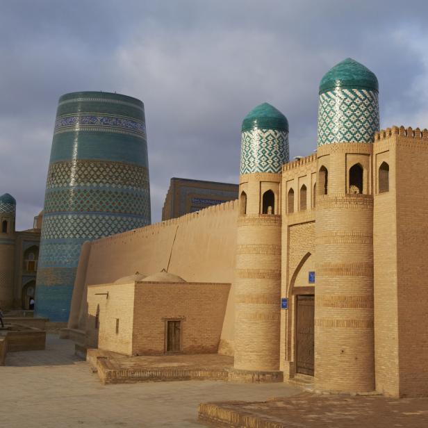 Die historische Architektur von Chiwa, Usbekistan, mit blaugrünen Kuppeln und Ziegelbauten.