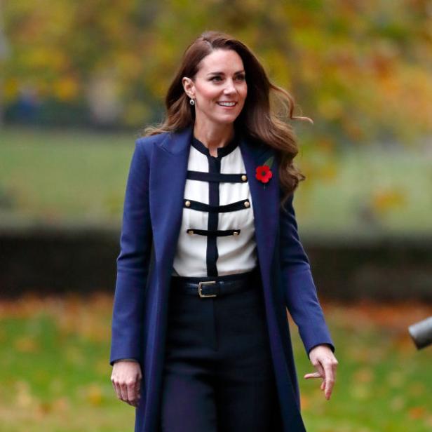 Kate Middleton in einem blauen Mantel und mit einer Mohnblume geschmückt.